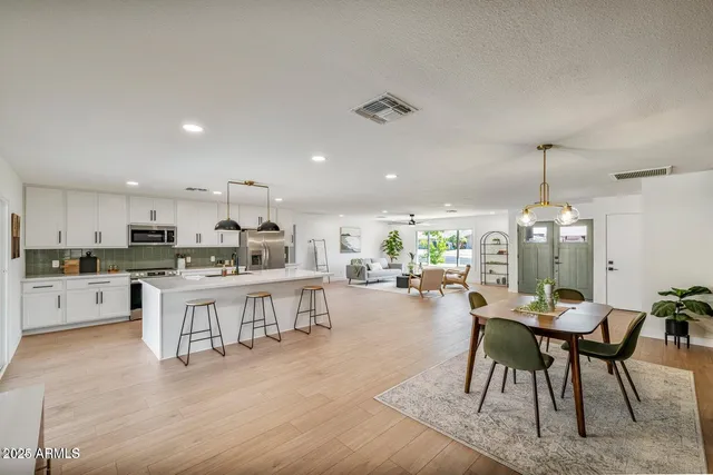 a kitchen with a dining table chairs stove refrigerator and cabinets