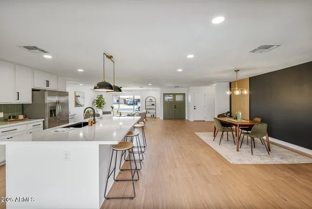 a kitchen with stainless steel appliances granite countertop a stove top oven a sink dishwasher a dining table and chairs with wooden floor