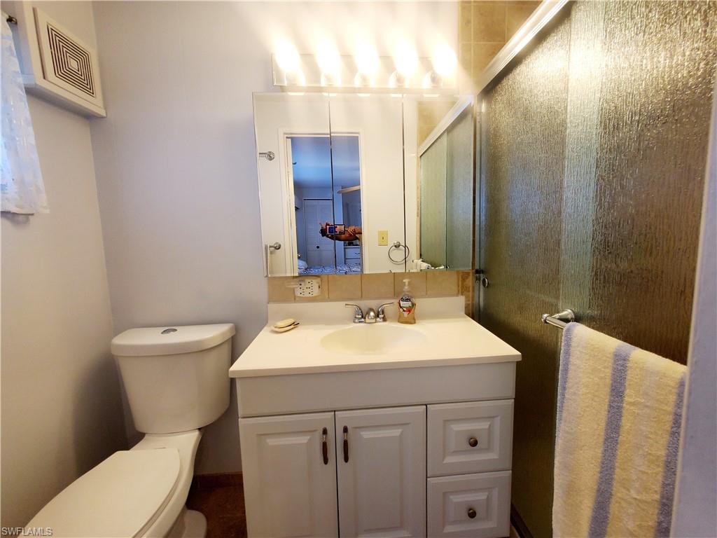 91 Enchanting Boulevard, Unit E91 Naples, FL 34112 - Photo 19 of 23 a bathroom with a sink a toilet a mirror and shower
