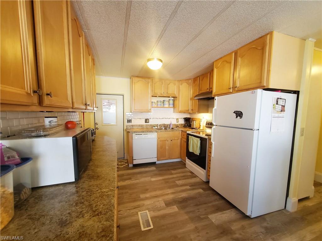 91 Enchanting Boulevard, Unit E91 Naples, FL 34112 - Photo 4 of 23 a kitchen with a refrigerator a sink and white cabinets