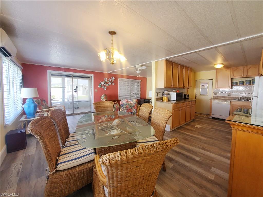 91 Enchanting Boulevard, Unit E91 Naples, FL 34112 - Photo 10 of 23 a view of a dining room with furniture a chandelier and wooden floor