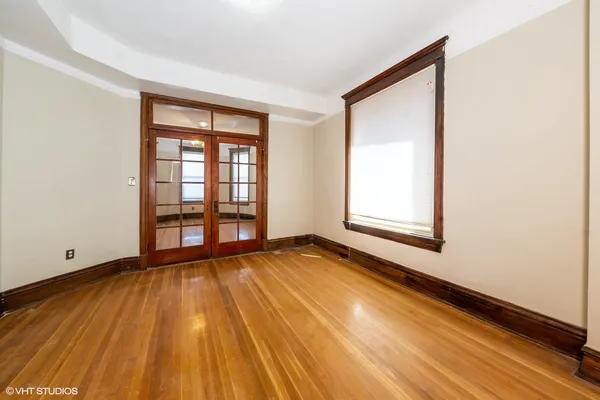 a view of an empty room with wooden floor and a window
