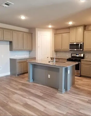 a kitchen with stainless steel appliances granite countertop a sink a stove a refrigerator cabinets and a window