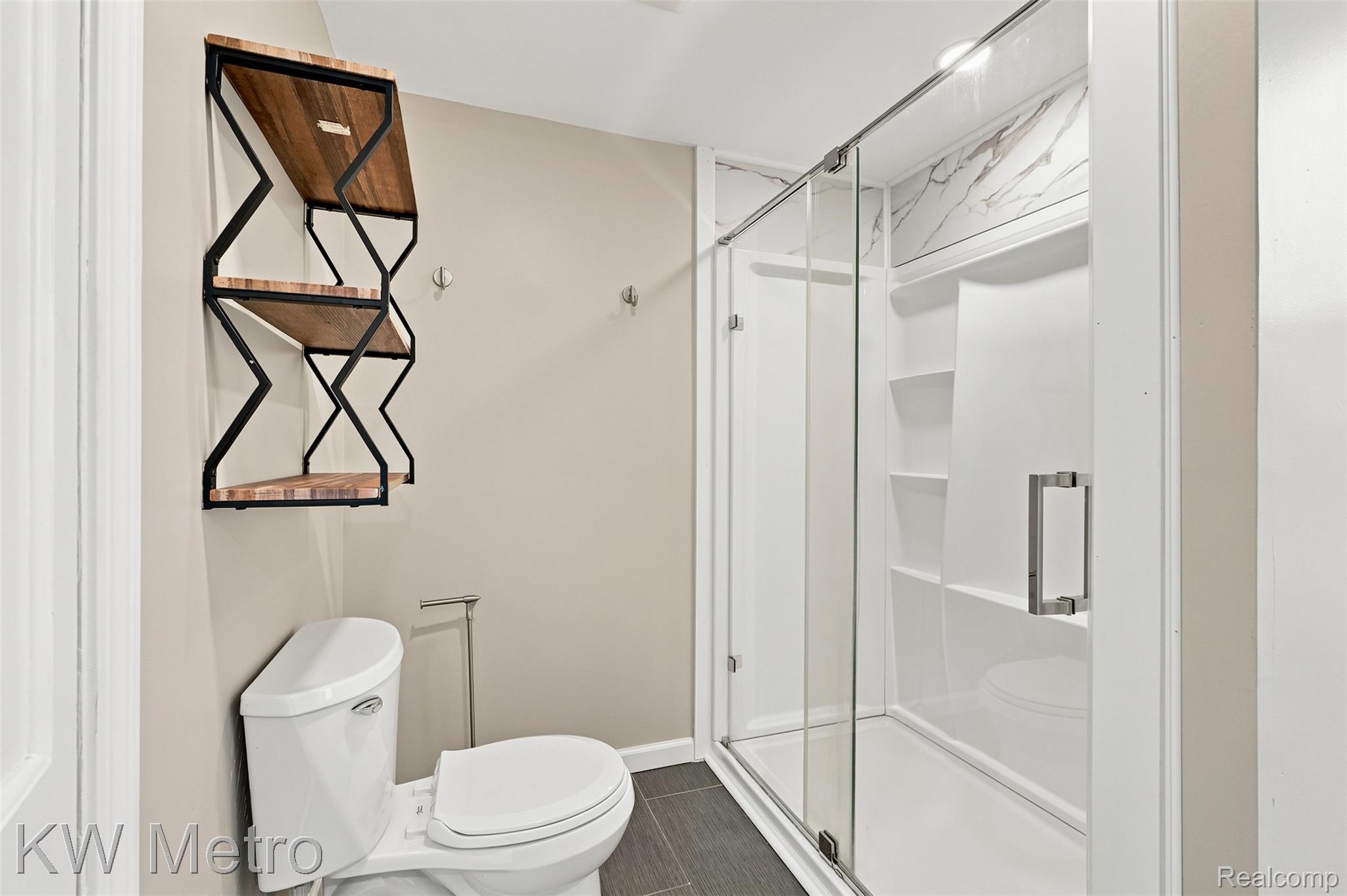 1458 Hampton Road Grosse Pointe, MI 48236 - Photo 25 of 43 Modern bathroom featuring a glass-enclosed shower with integrated shelving and a white marble-patterned surround