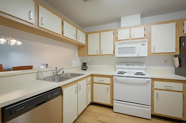 a kitchen with white cabinets appliances a sink and a counter space