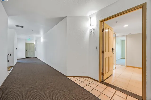 a view of a hallway with wooden floor and a bathroom