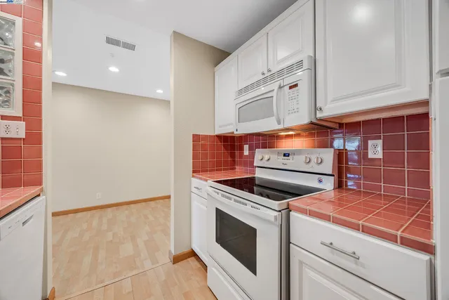 a kitchen with granite countertop white cabinets and white appliances