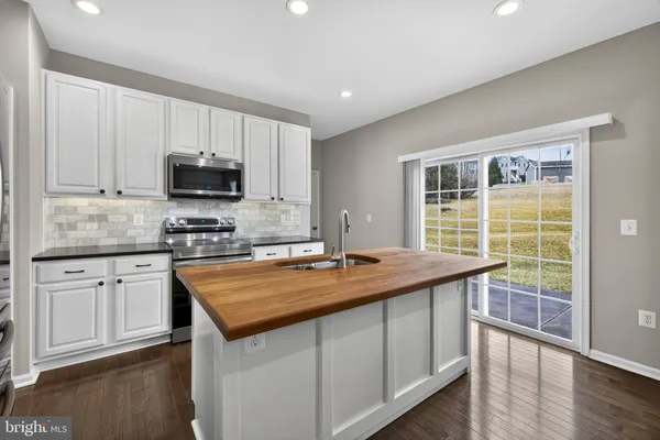a kitchen with kitchen island granite countertop a sink a stove oven and refrigerator