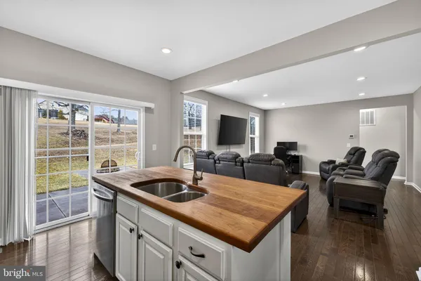 a kitchen with stainless steel appliances granite countertop a sink a stove a refrigerator and a dining table with wooden floor