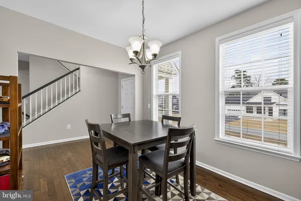 a dining room with wooden floor a chandelier a wooden table and chairs