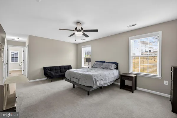 a spacious bedroom with a bed a couch and a chandelier