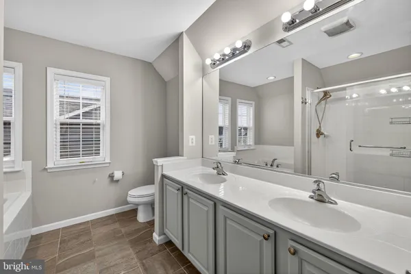 a spacious bathroom with a double vanity sink a mirror a bathtub and shower