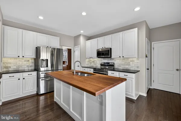 a kitchen with kitchen island a counter space a sink appliances and cabinets