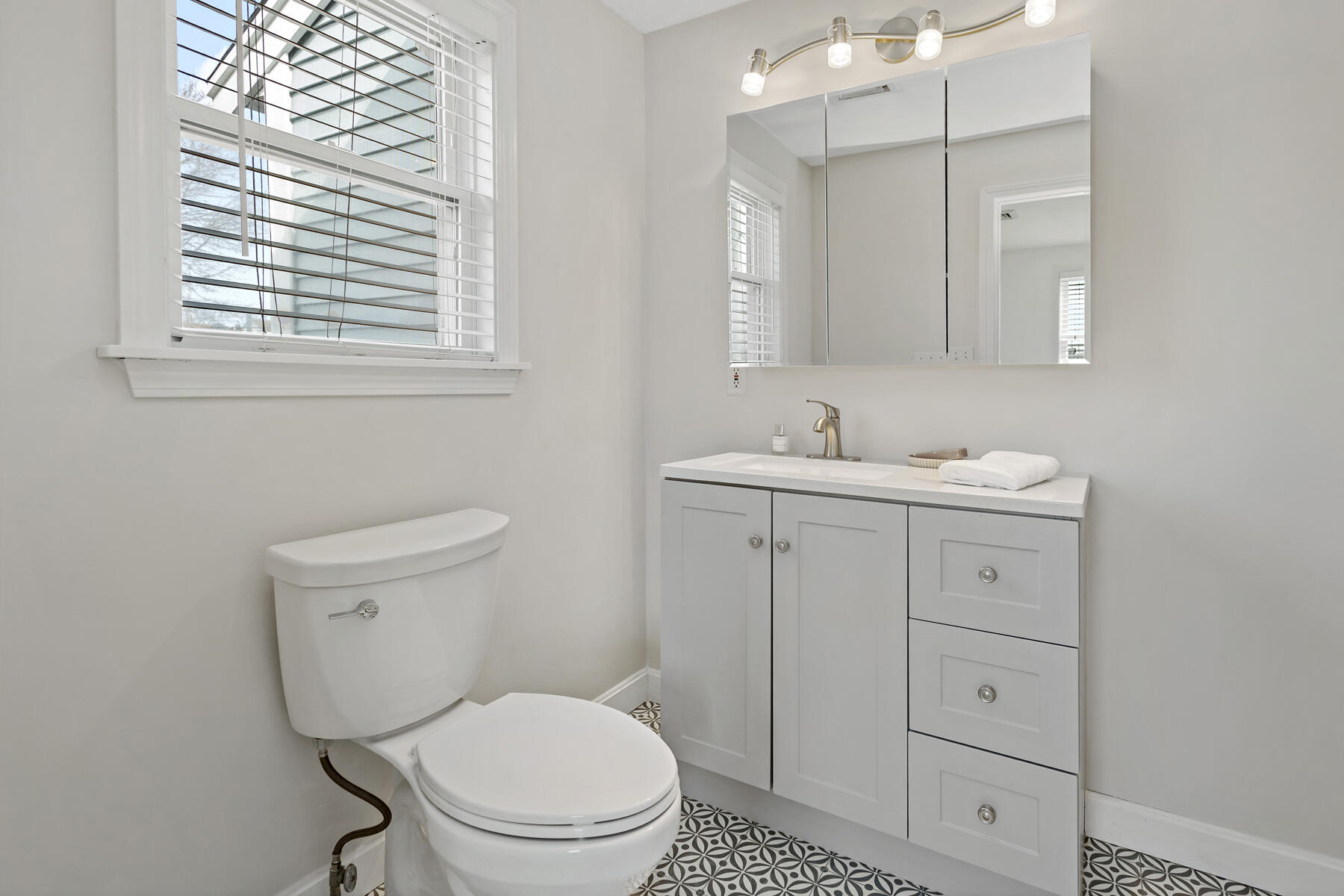 20 Evergreen Street Onset, MA 02558 - Photo 16 of 26 a bathroom with a toilet a sink a vanity a mirror and a window