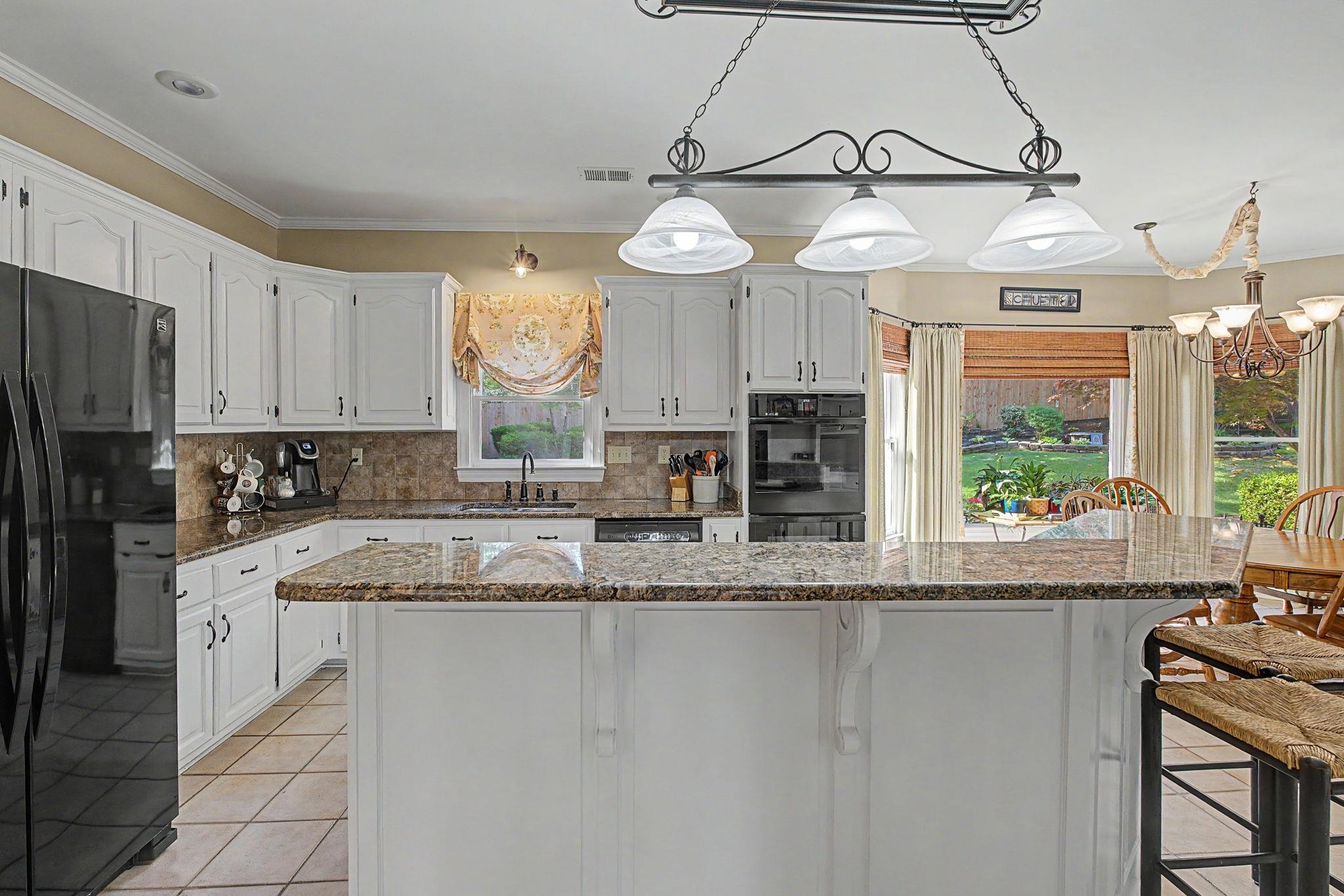 337 Revell Cove Collierville, TN 38017 - Photo 12 of 40 a large kitchen with granite countertop a stove a sink a window and stainless steel appliances