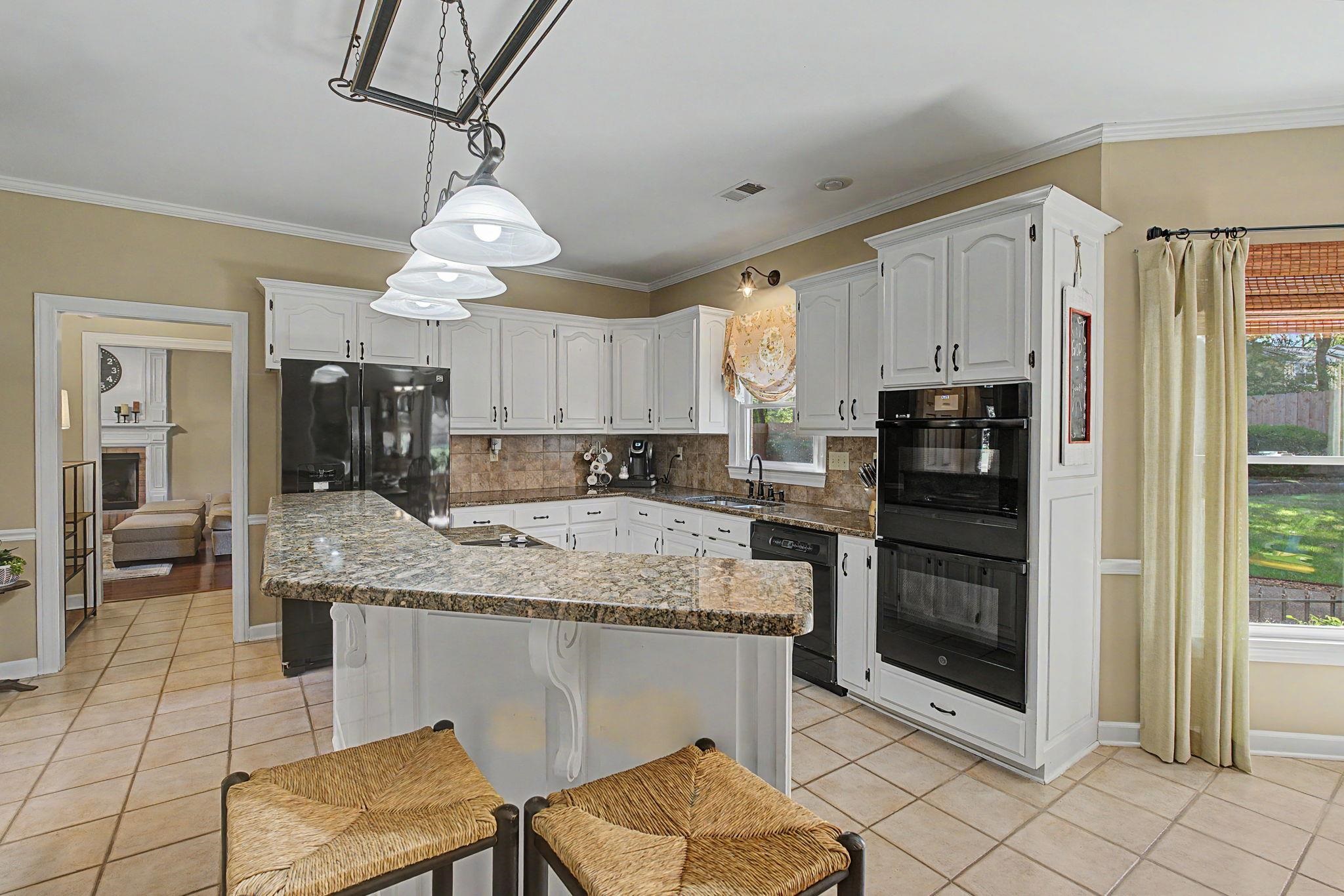 337 Revell Cove Collierville, TN 38017 - Photo 13 of 40 a kitchen with stainless steel appliances granite countertop a stove a refrigerator a oven with white cabinets and wooden floor