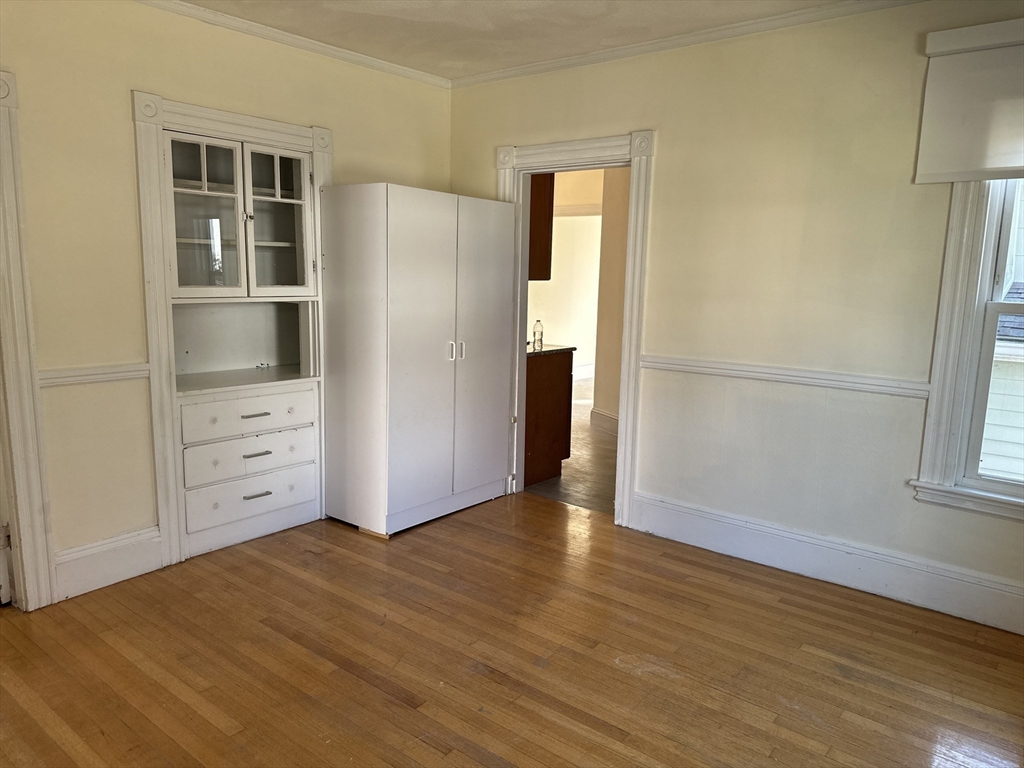 90 Russell Street, Unit 90 Melrose, MA 02176 - Photo 5 of 9 an empty room with cabinet and wooden floor