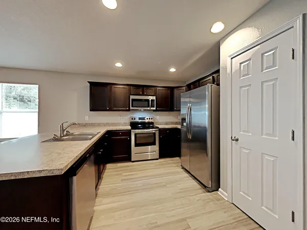 a kitchen with stainless steel appliances granite countertop a refrigerator a sink a stove and oven