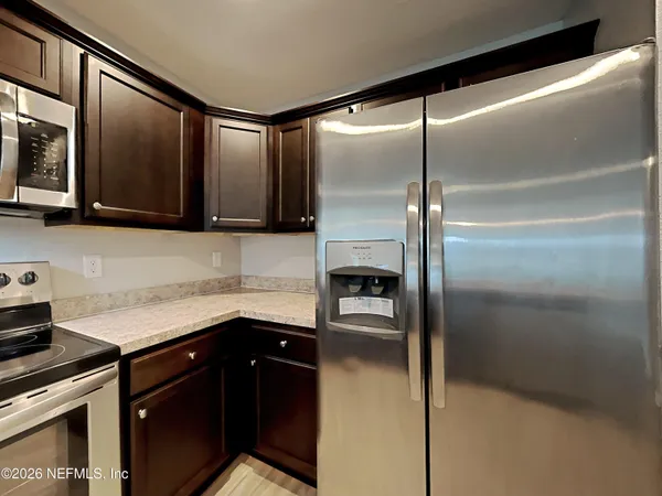 a kitchen with stainless steel appliances granite countertop a refrigerator a stove and a sink with wooden floor