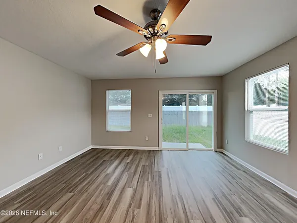 a view of an empty room with wooden floor and a window
