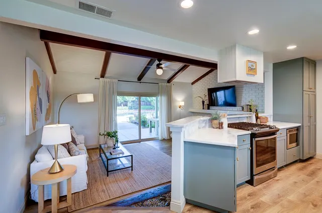a kitchen with a stove a refrigerator sink dishwasher and fireplace with wooden floor