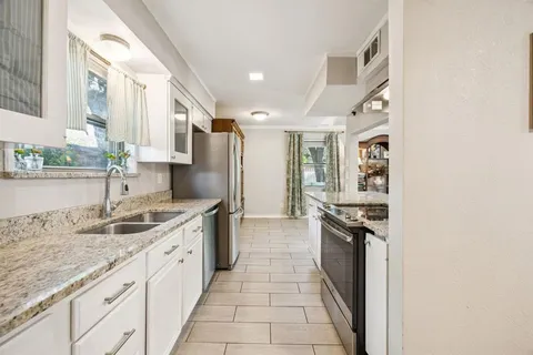 a kitchen with granite countertop a sink stove and refrigerator