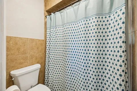a bathroom with a toilet and a shower curtain