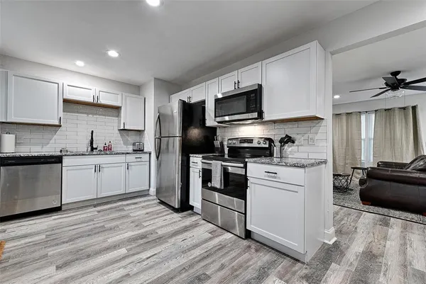 a kitchen with a sink white cabinets and stainless steel appliances