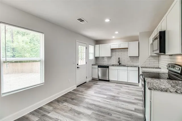 a kitchen with granite countertop white cabinets and white appliances