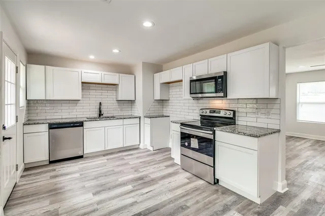 a kitchen with a stove top oven a sink and white cabinets