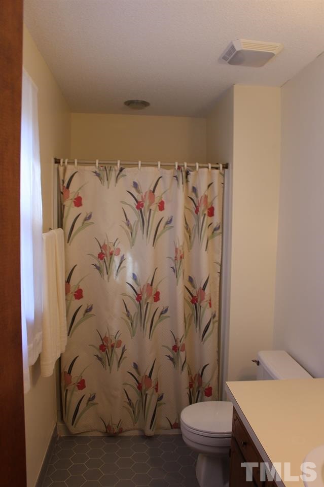 8709 Campfire Trail Raleigh, NC 27615 - Photo 15 of 25 a bathroom with a toilet and a shower curtain