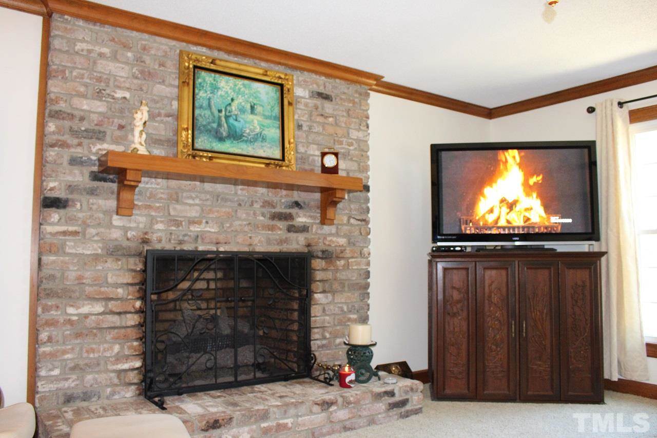 8709 Campfire Trail Raleigh, NC 27615 - Photo 9 of 25 a living room with fireplace and a flat screen tv