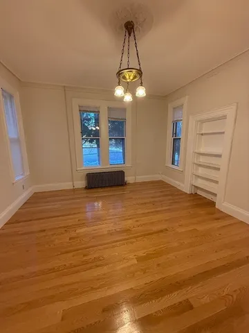 a view of an empty room with a window and wooden floor