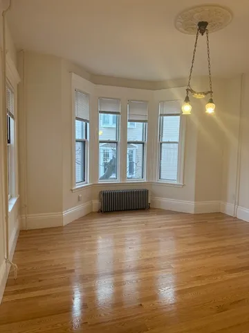 a view of an empty room with window and wooden floor