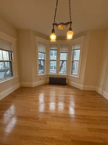 a view of an empty room with window and wooden floor