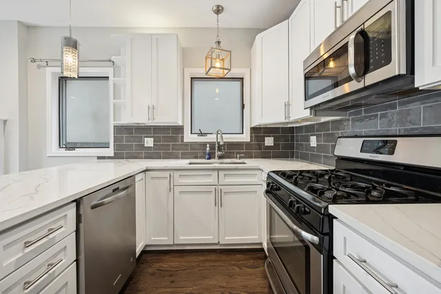 a kitchen with stainless steel appliances granite countertop a stove a sink and a microwave