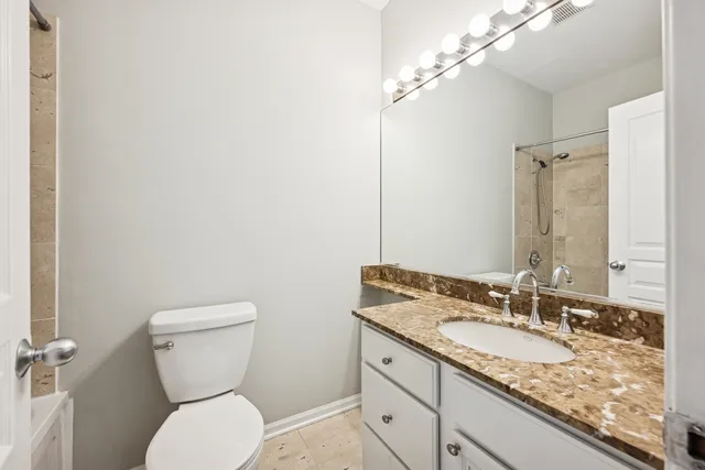 a bathroom with a granite countertop toilet sink and mirror