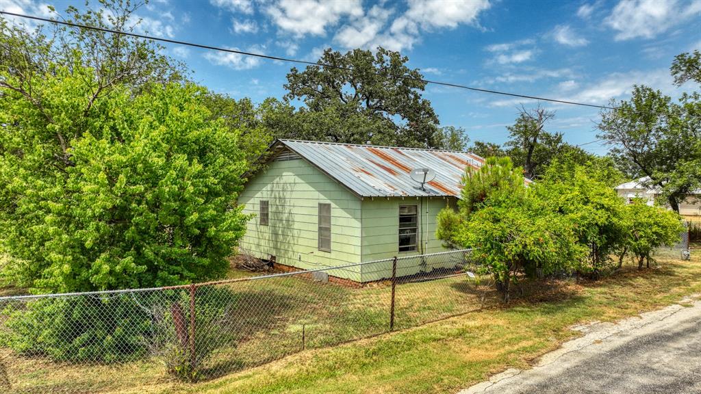 62 Travis Street Santo, TX 76472 - Photo 3 of 9 a view of a house with a small yard and wooden fence