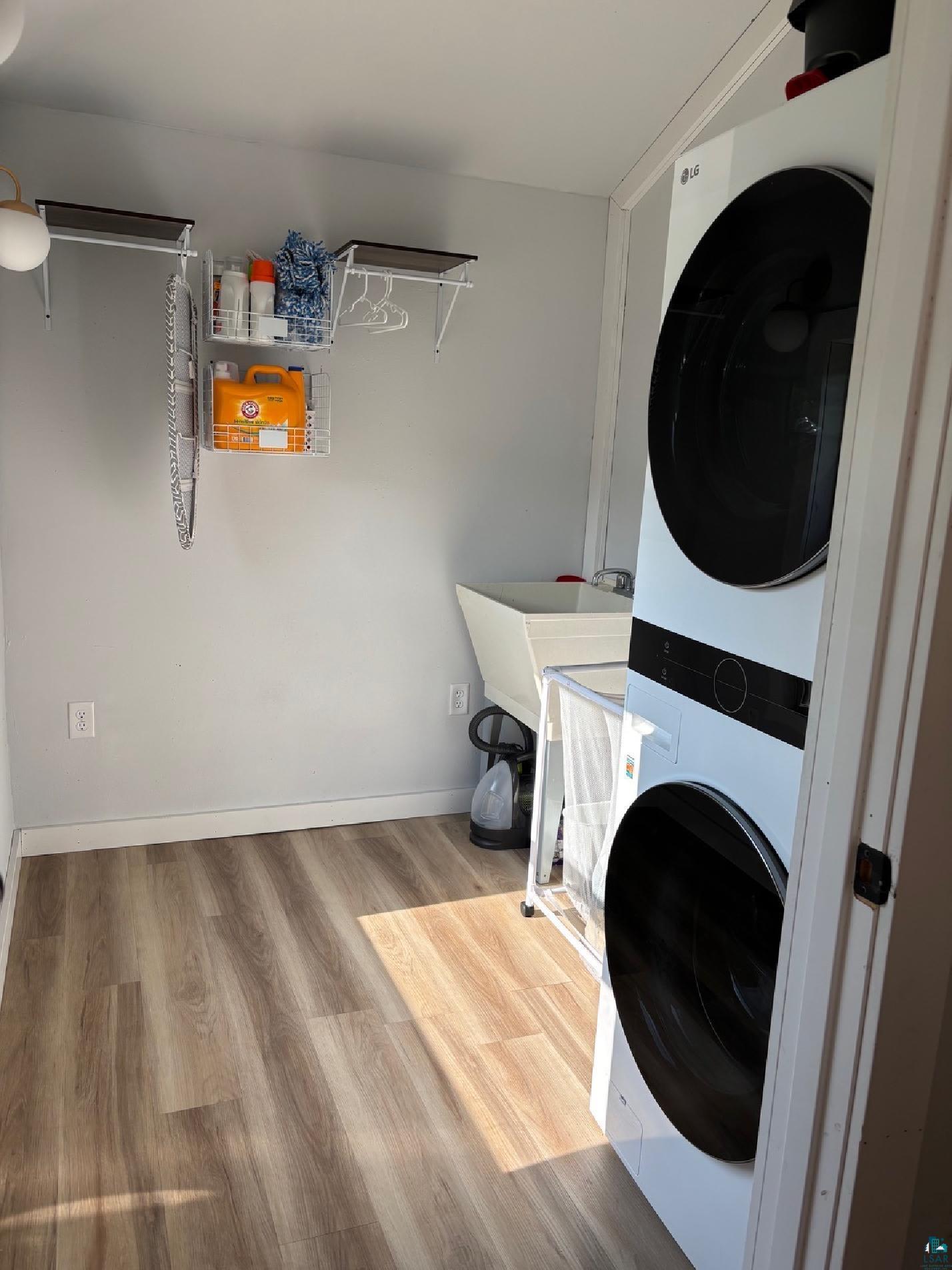 701 Drake Street Mellen, WI 54546 - Photo 15 of 27 Dedicated laundry area featuring a stacked washer and dryer unit, wood-finish flooring, and a utility sink