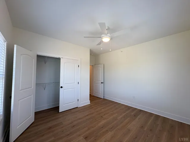 an empty room with wooden floor and ceiling fan