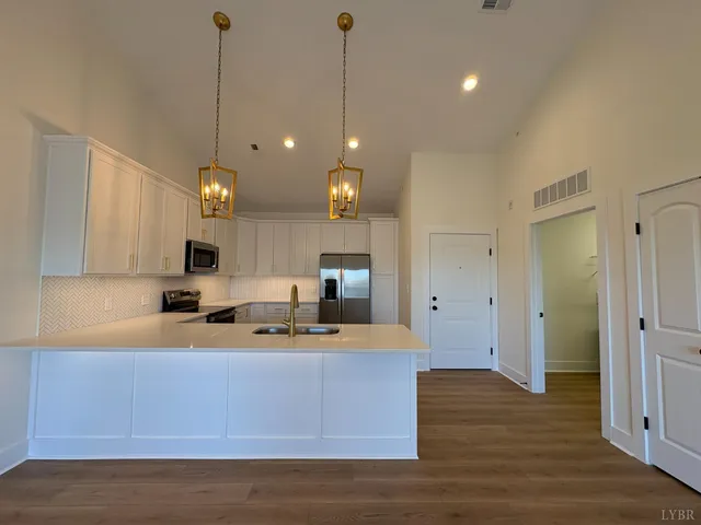 a kitchen with kitchen island stainless steel appliances a stove a sink cabinets and wooden floor