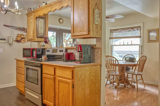 a kitchen with stainless steel appliances granite countertop a stove top oven a sink a dining table and chairs