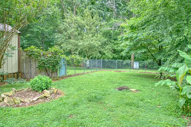 a view of backyard with green space and wooden fence