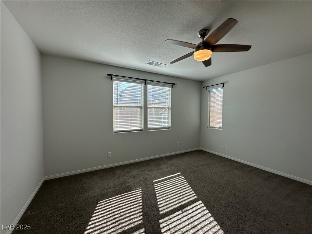 11585 Salt Creek Avenue Las Vegas, NV 89138 - Photo 12 of 45 Empty room with plenty of natural light, dark colored carpet, a textured ceiling, and ceiling fan