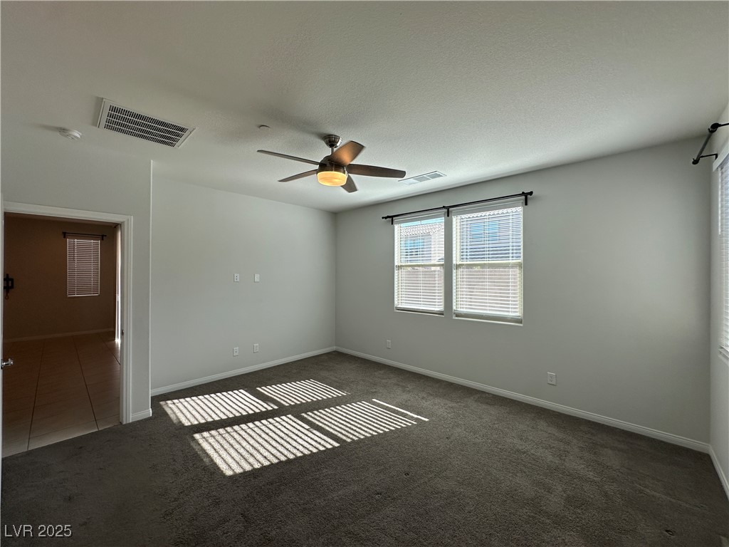 11585 Salt Creek Avenue Las Vegas, NV 89138 - Photo 14 of 45 Spare room featuring dark carpet, ceiling fan, and a textured ceiling