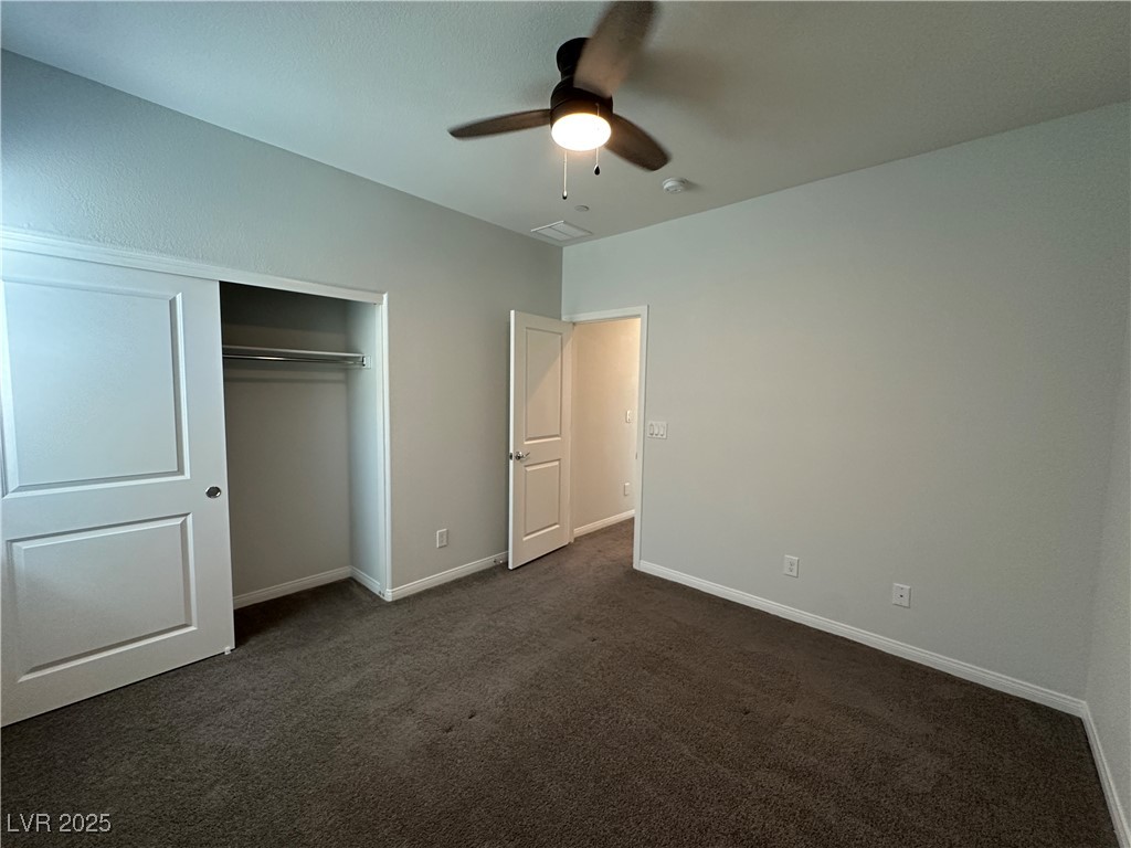 11585 Salt Creek Avenue Las Vegas, NV 89138 - Photo 32 of 45 Unfurnished bedroom with dark colored carpet, a ceiling fan, and a closet