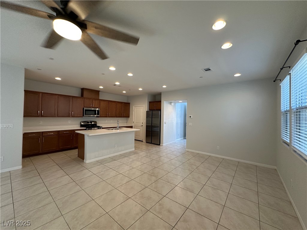 11585 Salt Creek Avenue Las Vegas, NV 89138 - Photo 9 of 45 Kitchen featuring light countertops, stainless steel appliances, an island with sink, recessed lighting, and light tile patterned floors