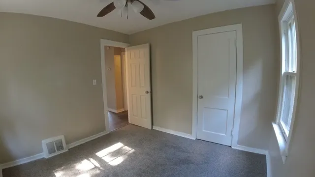 a view of an empty room with window and wooden floor