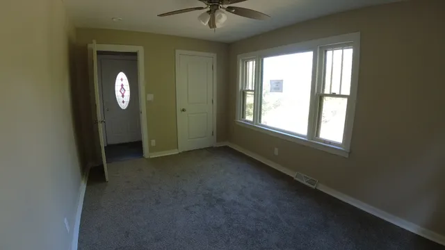 an empty room with a window and a fan
