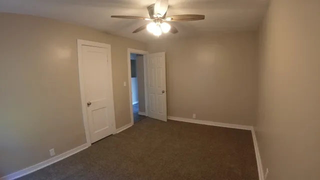 an empty room with closet and a ceiling fan